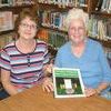Becky Mondrage (left) and Jean Raines have worked tirelessly to organize the fourth annual Sandlick Homecoming. Raines displays a community cookbook created especially for the celebration, along with a calendar, which includes the history of Sandlick and stories about some of its people.