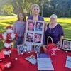 Organizers Rose Mary Holbrook, Gina Owens Stanley and Crystal Craft display photos of domestic violence victims.  LISA MAINE PHOTO